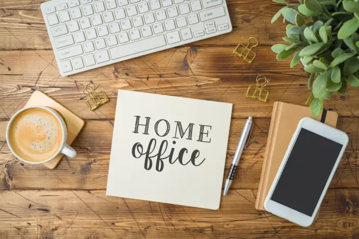 desk featuring a working station with coffee, a phone, pencil, a keyboard
