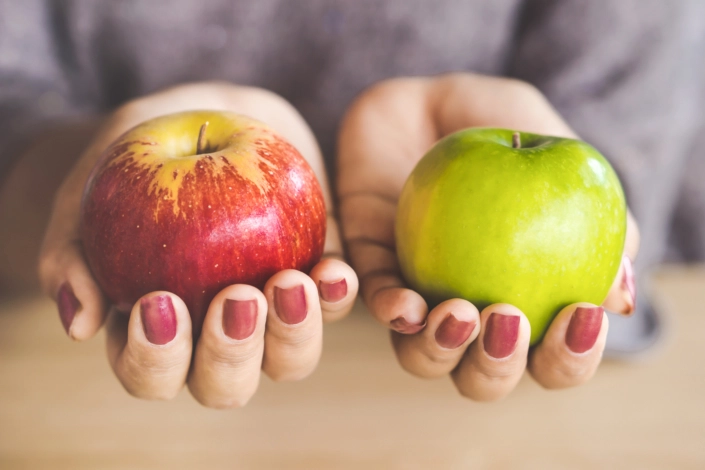 woman holding one red apple and a green apple